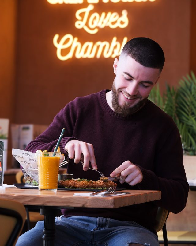 Client savourant son repas avec néon Crêpe Touch en arrière-plan
