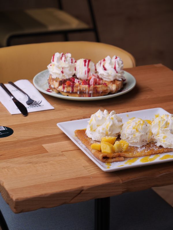 Crêpes sucrées garnies de chantilly et fruits sur table en bois